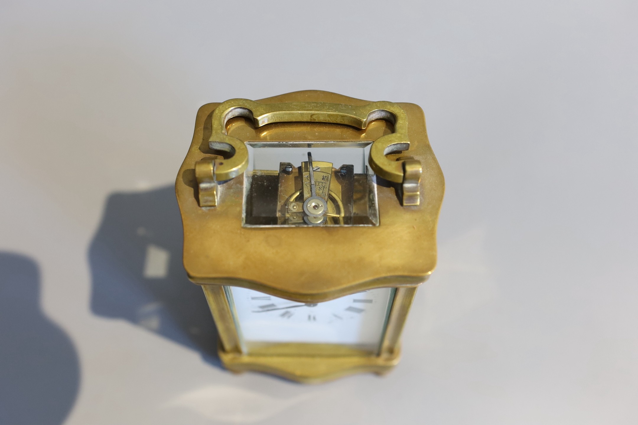 An early 20th century French lacquered brass carriage timepiece, of serpentine form, in red morocco case, height 12cm